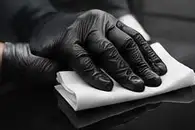 Gloved hand doing a panel wipe with a white towel