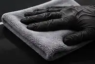 Gloved hand wiping paint with a gray microfiber towel